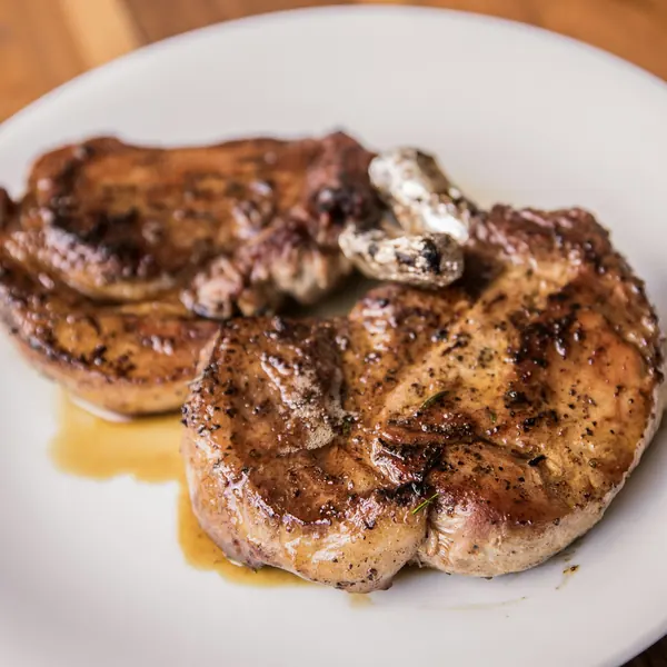 Two browned pork chops on a white plate