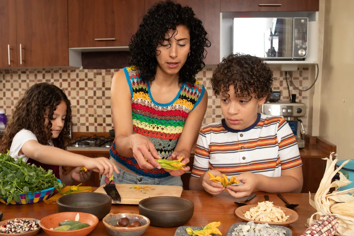 A parent and two children preparing a meal together in their kitchen